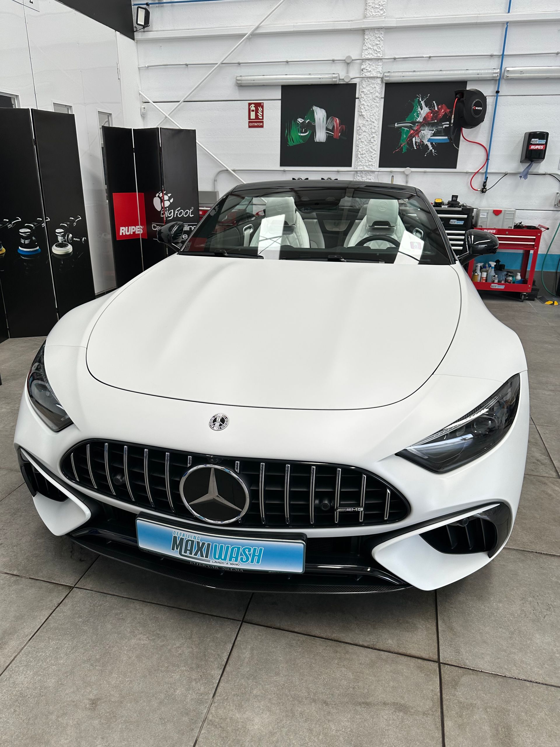 Un coche deportivo Mercedes Benz blanco está aparcado en un garaje.