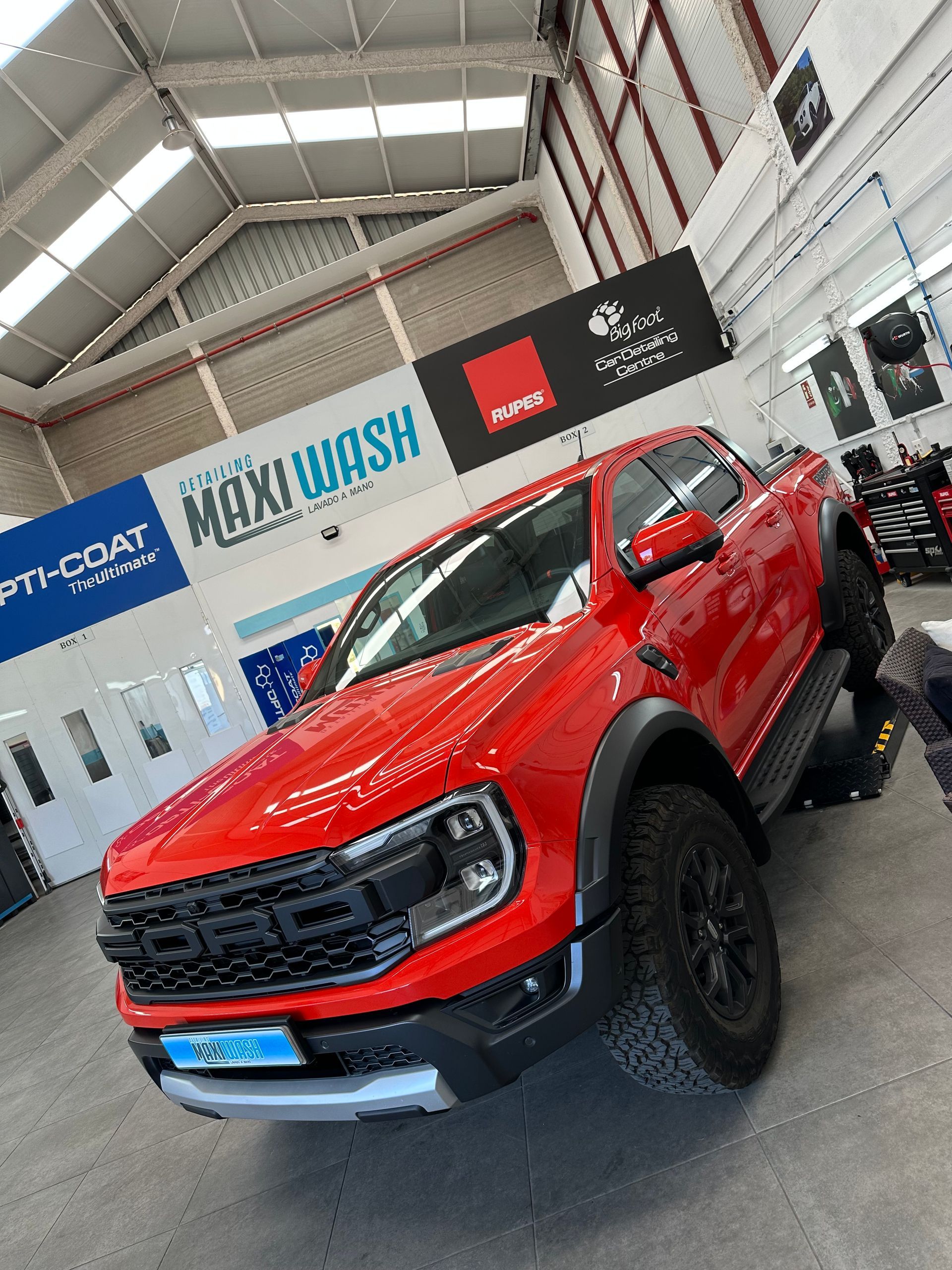 Un Ford Raptor rojo está estacionado en un garaje.