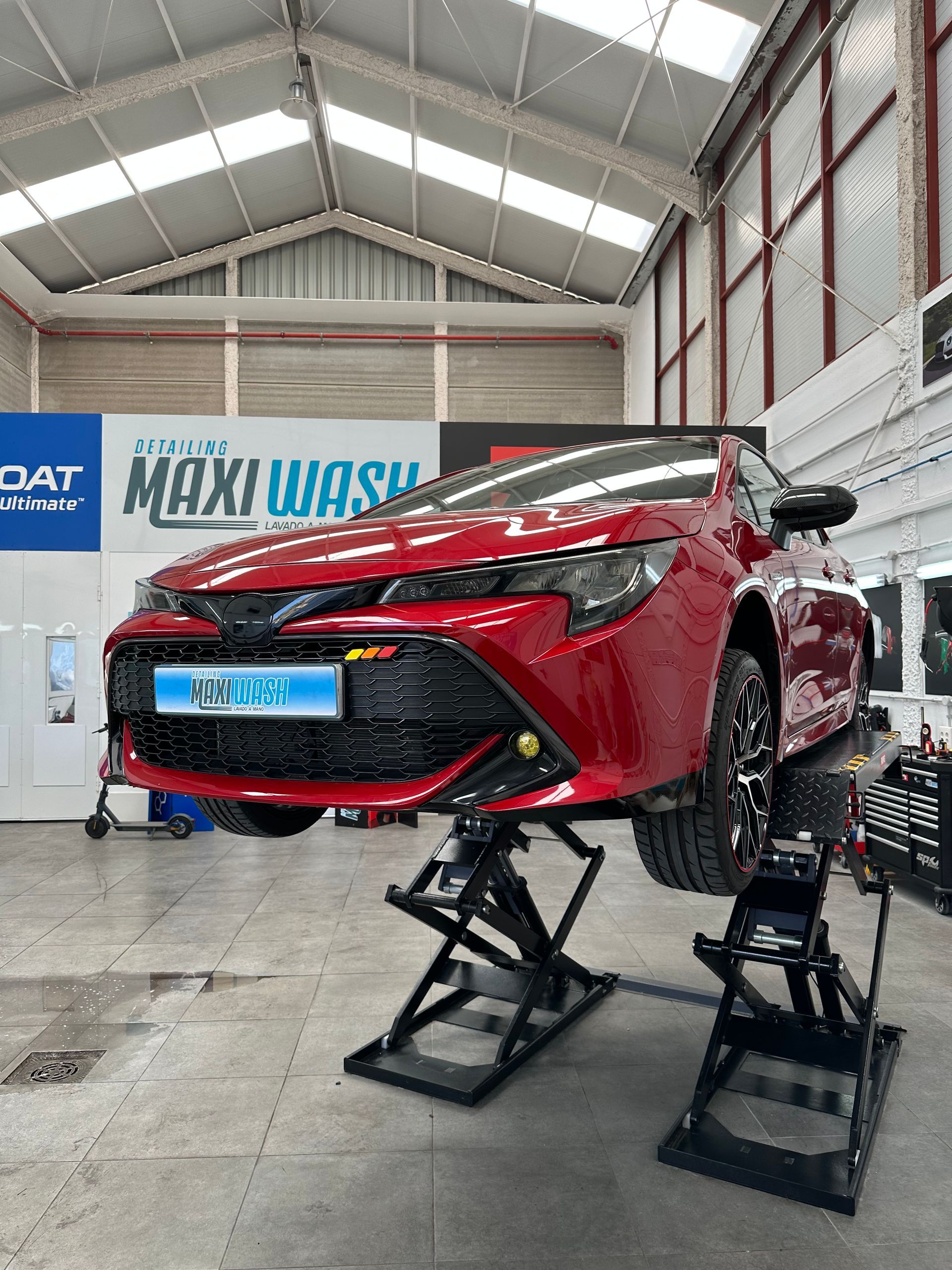 Un coche rojo está estacionado en un elevador en un garaje.