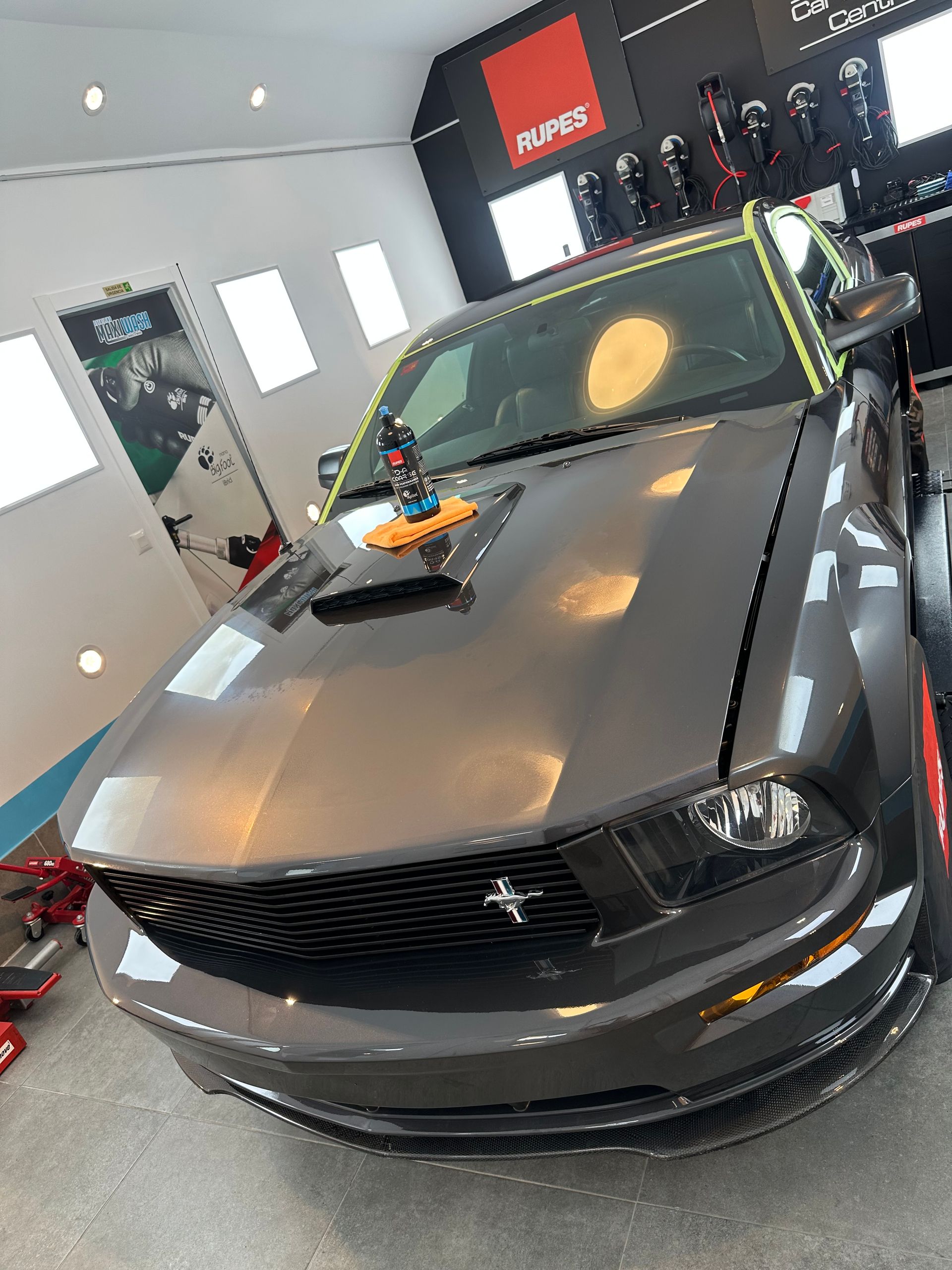 Un mustang gris está estacionado en un garaje.