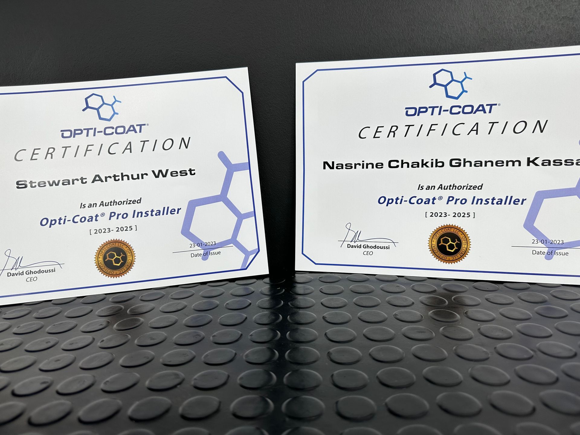 Dos certificados de certificación Opti-Coat se encuentran sobre una superficie negra