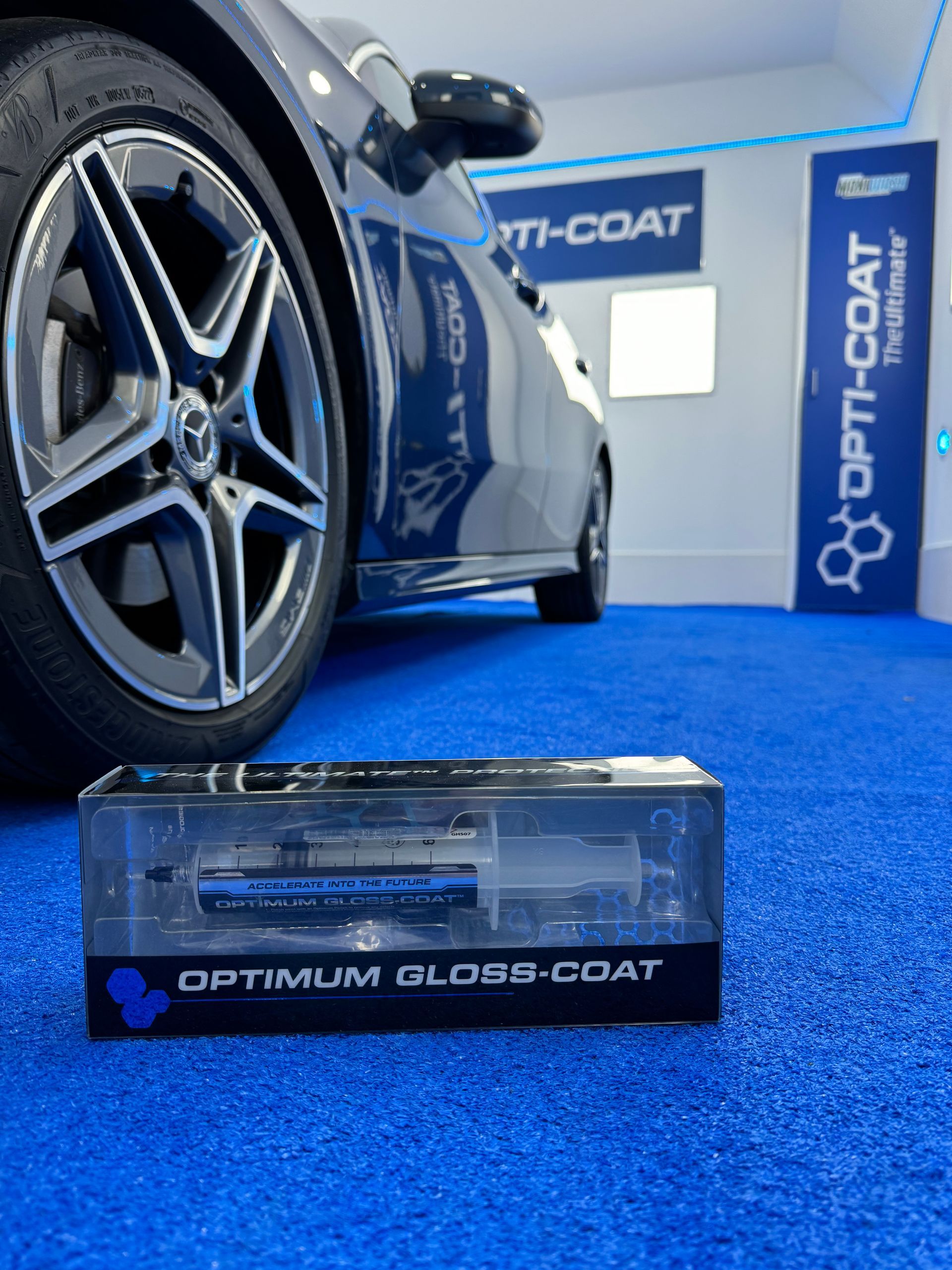 Un coche está aparcado junto a una caja de barniz de brillo óptimo.