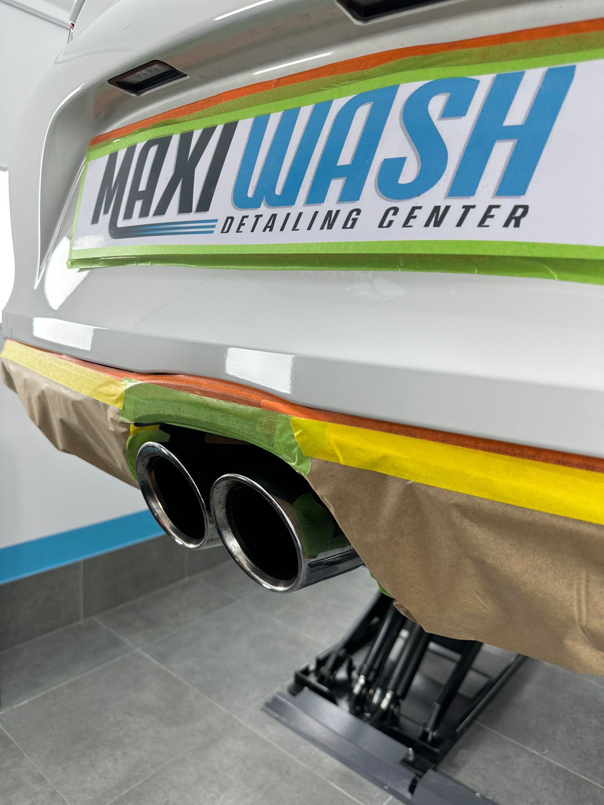 Un coche con un cartel que dice Maxi Wash Detailing Center