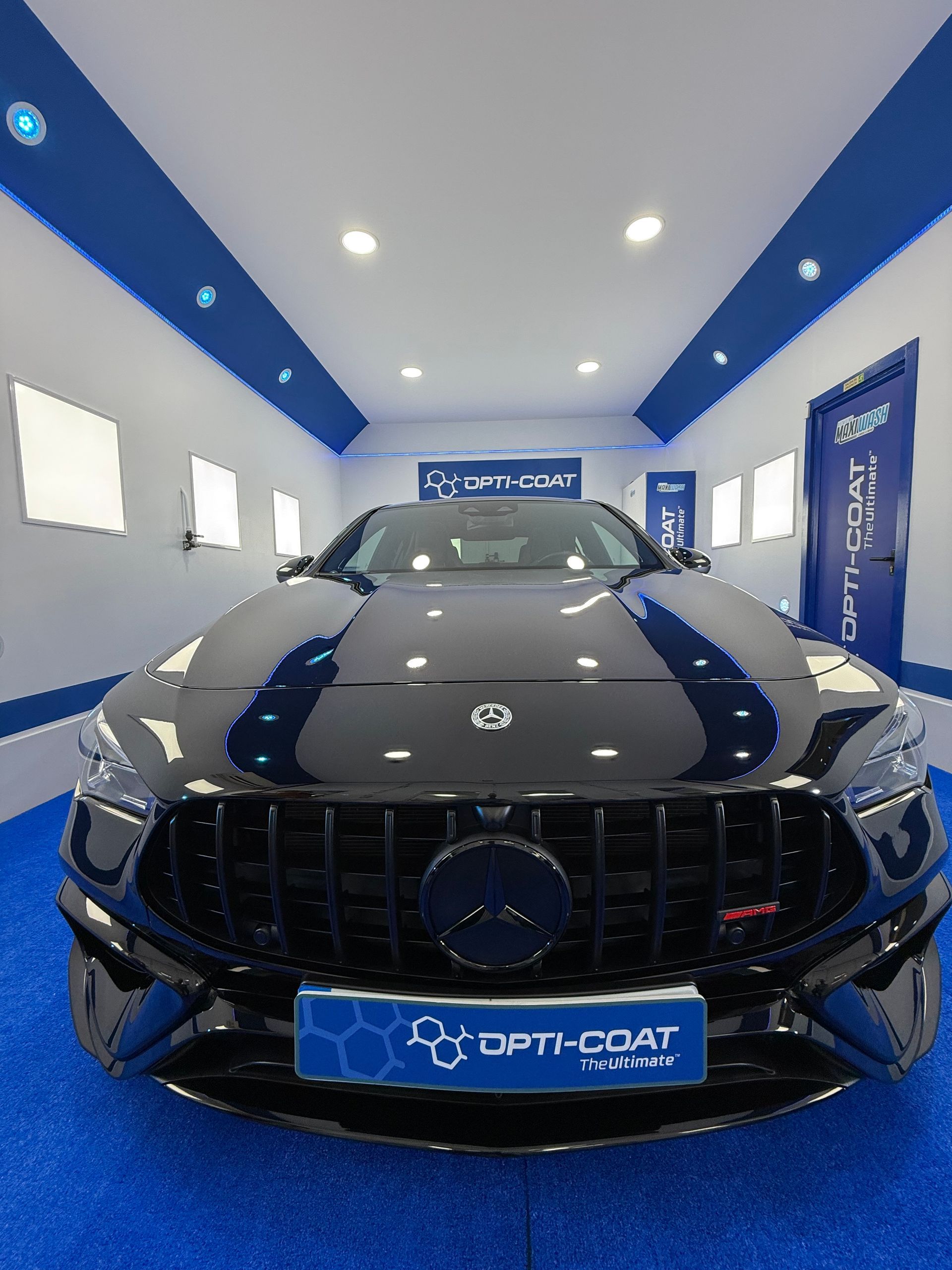 Un coche negro está aparcado en una habitación con alfombra azul.