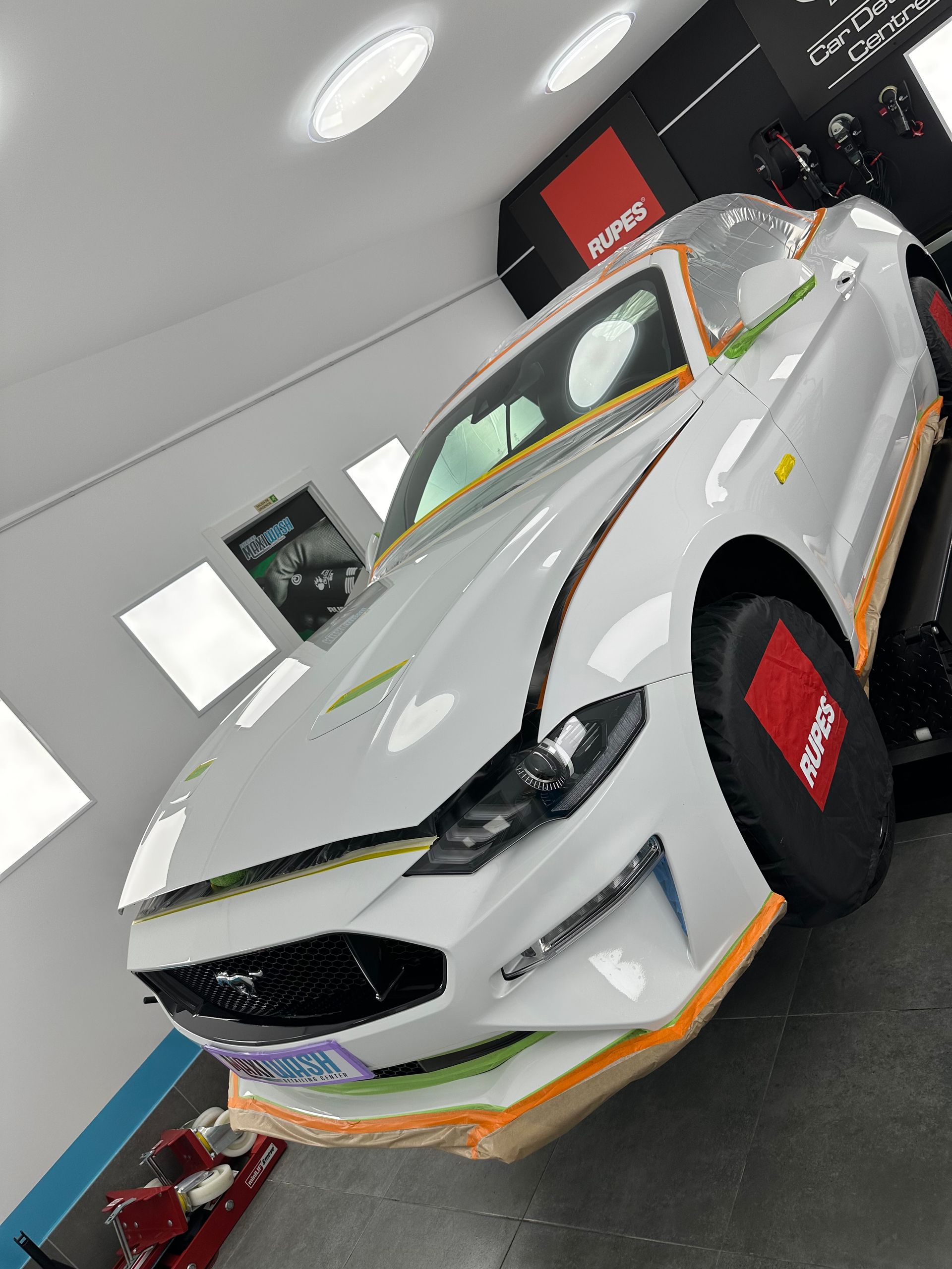 Un Ford Mustang blanco está estacionado en un garaje.