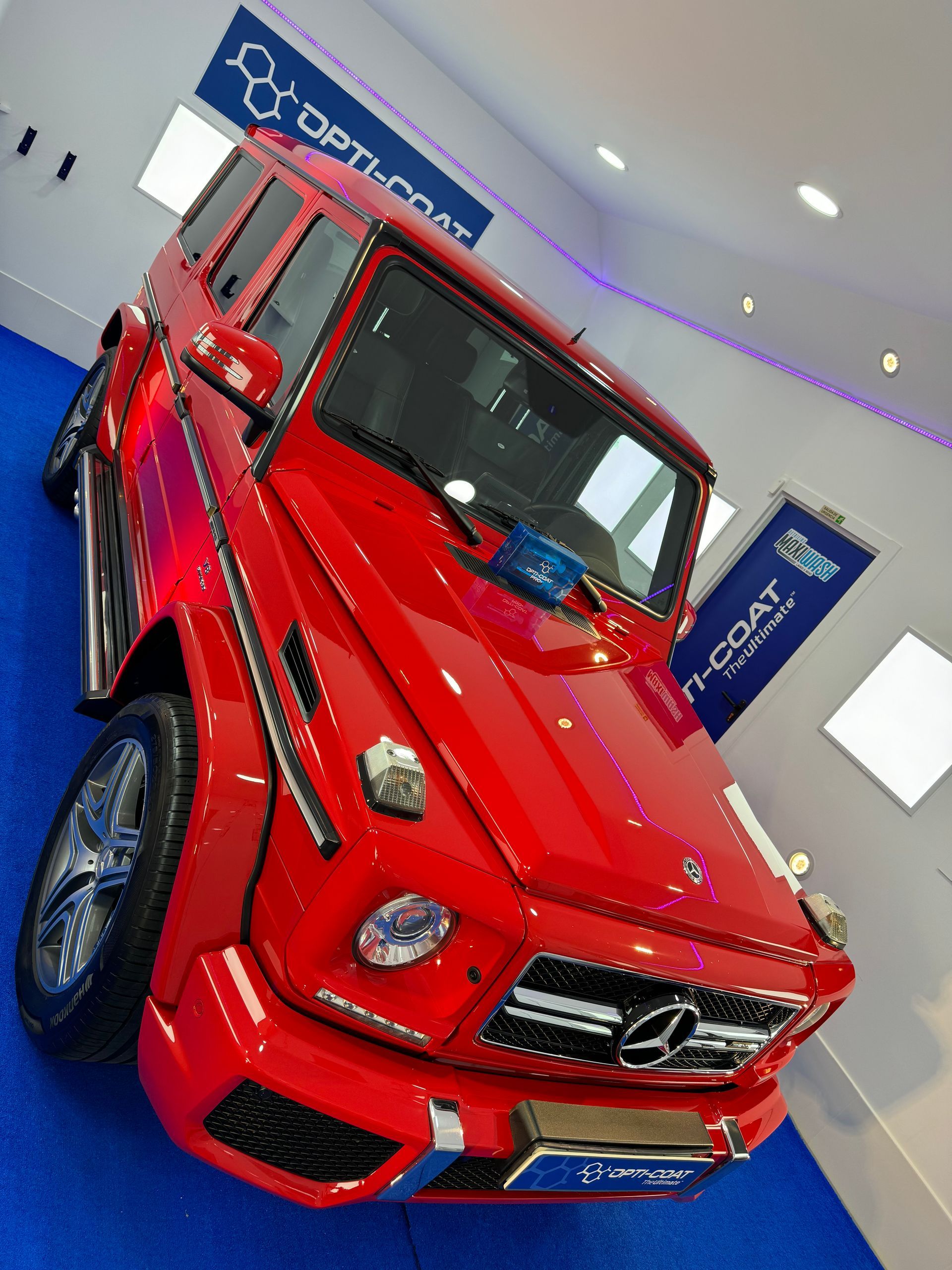 Un Mercedes Clase G rojo está estacionado sobre un piso azul.