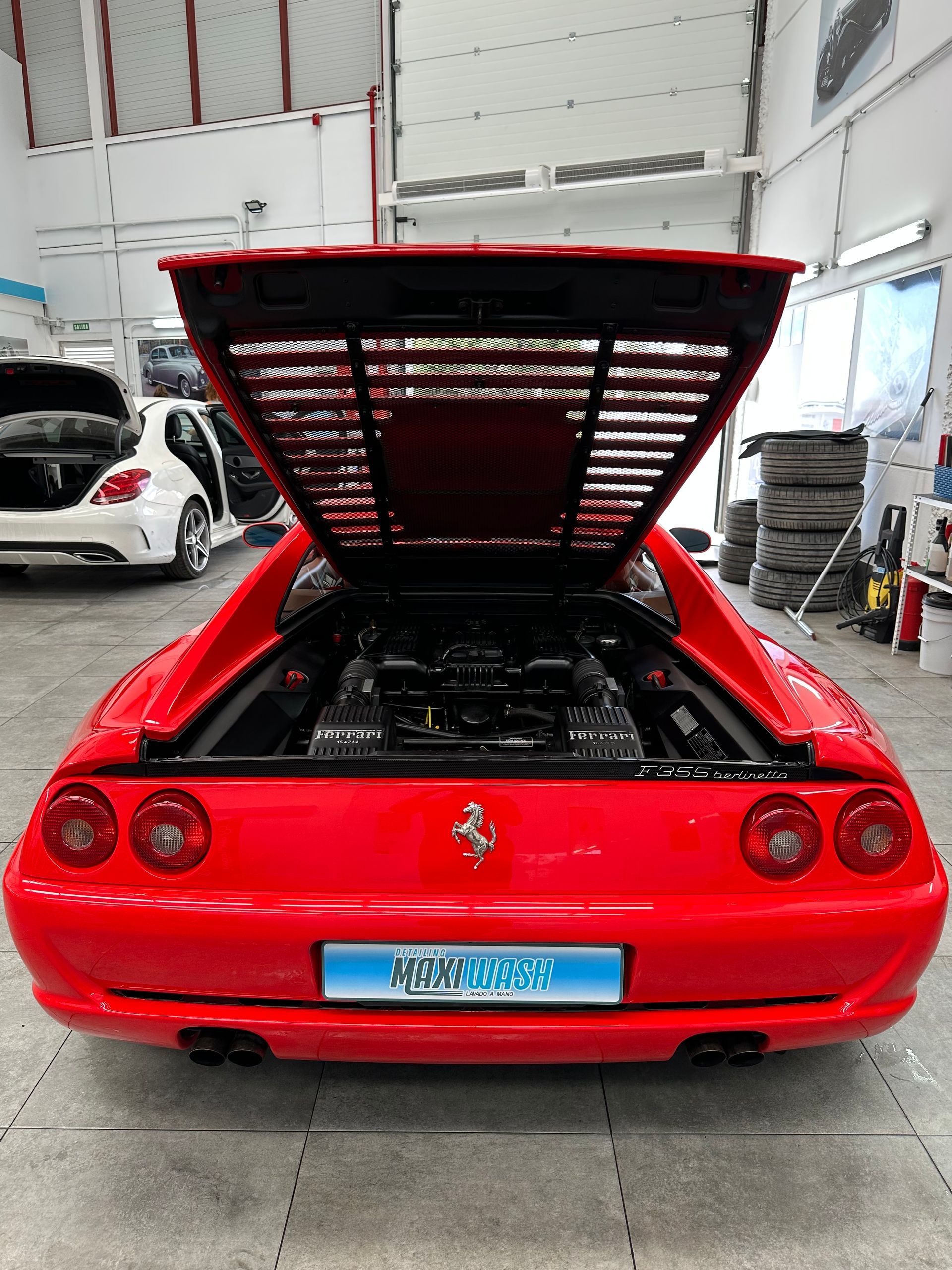Un Ferrari rojo con el capó levantado en un garaje.