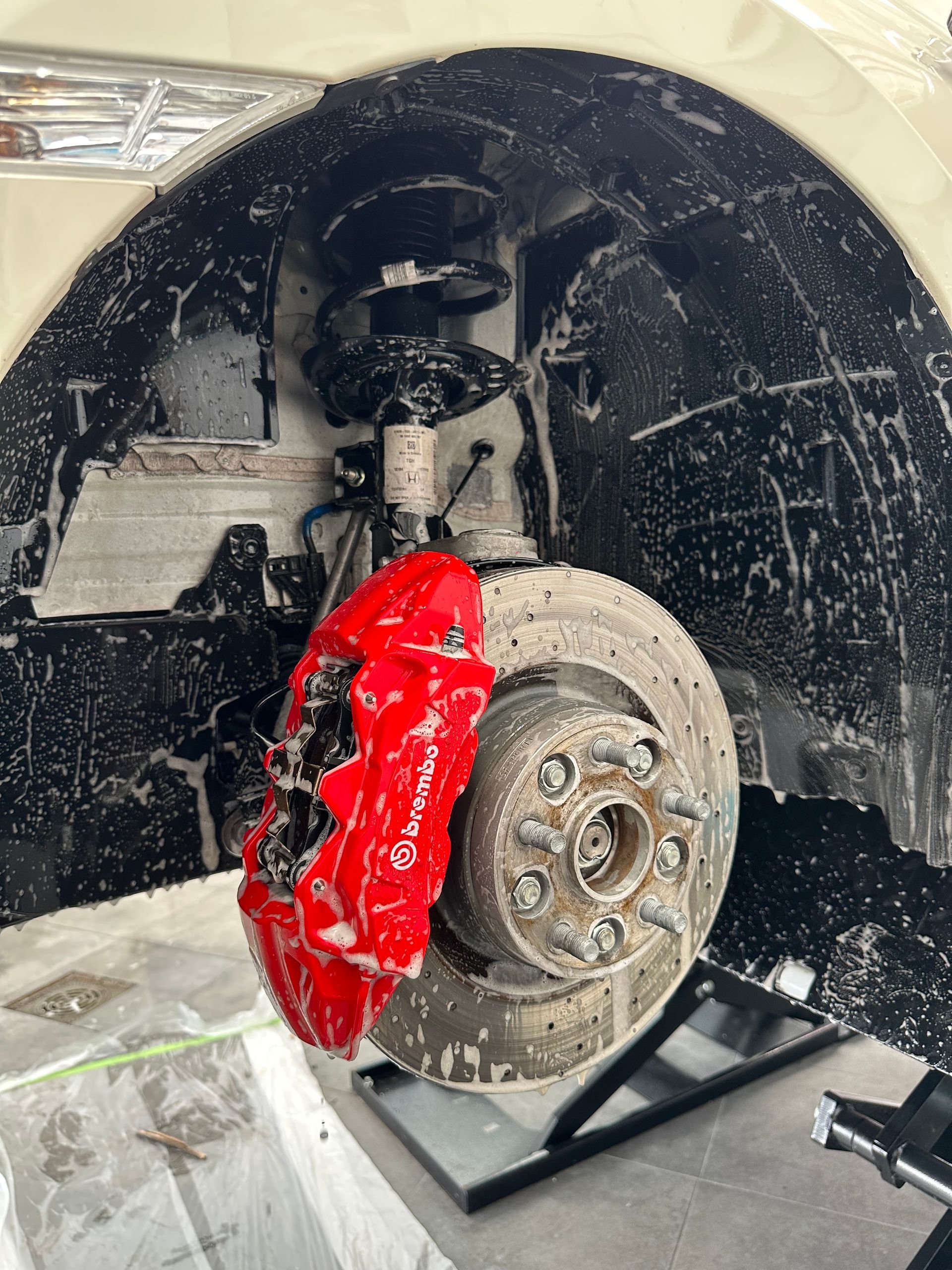 Un coche con una pinza de freno roja está parado en un elevador.