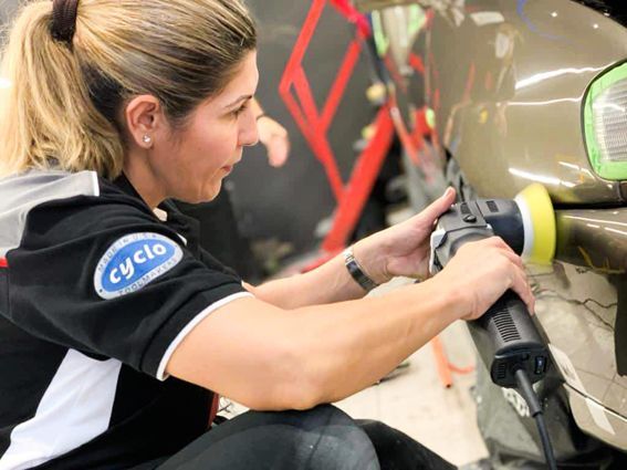 Una mujer está puliendo un coche con una máquina.