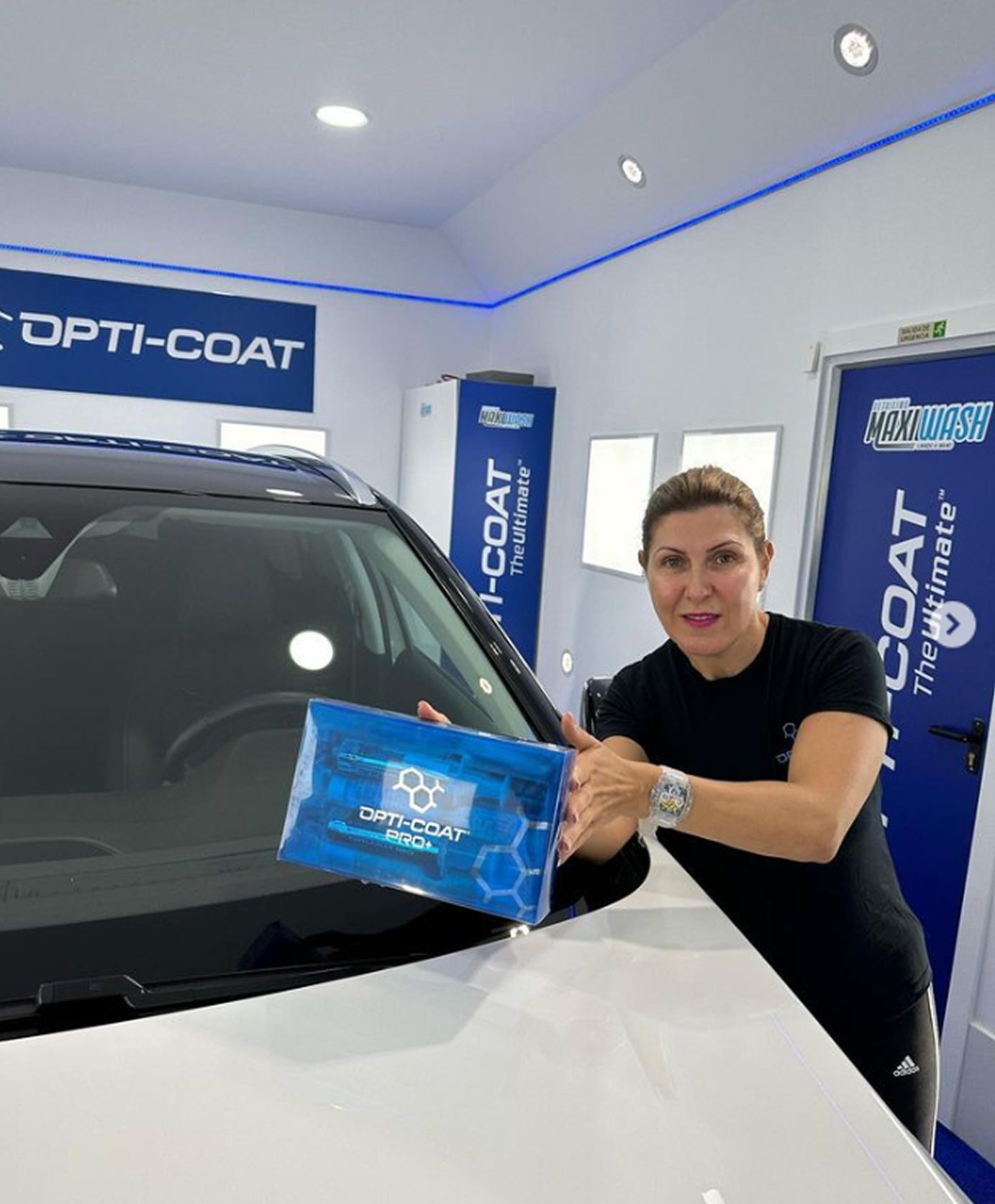 Una mujer está parada al lado de un automóvil sosteniendo un paquete de toallitas.