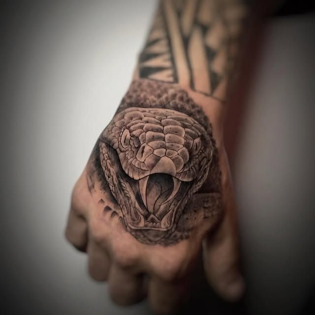 Mano tatuada con un gran tatuaje de serpiente en el dorso, primer plano.