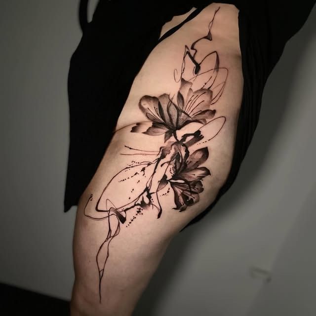 Tatuaje de líneas florales negras en el antebrazo de una persona sobre un fondo neutro.