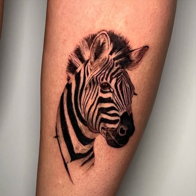 Tatuaje de cabeza de cebra en blanco y negro sobre la piel, mirando hacia la derecha.
