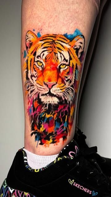 Un colorido tatuaje de tigre en la parte inferior de la pierna, encima de una zapatilla negra y un calcetín blanco.
