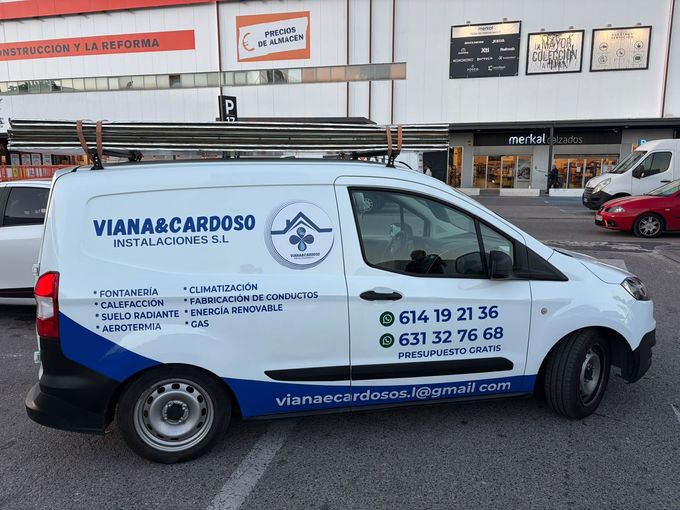 Furgoneta de transporte blanca y azul con la marca «VIANA CARDOSO» aparcada frente a un local comercial