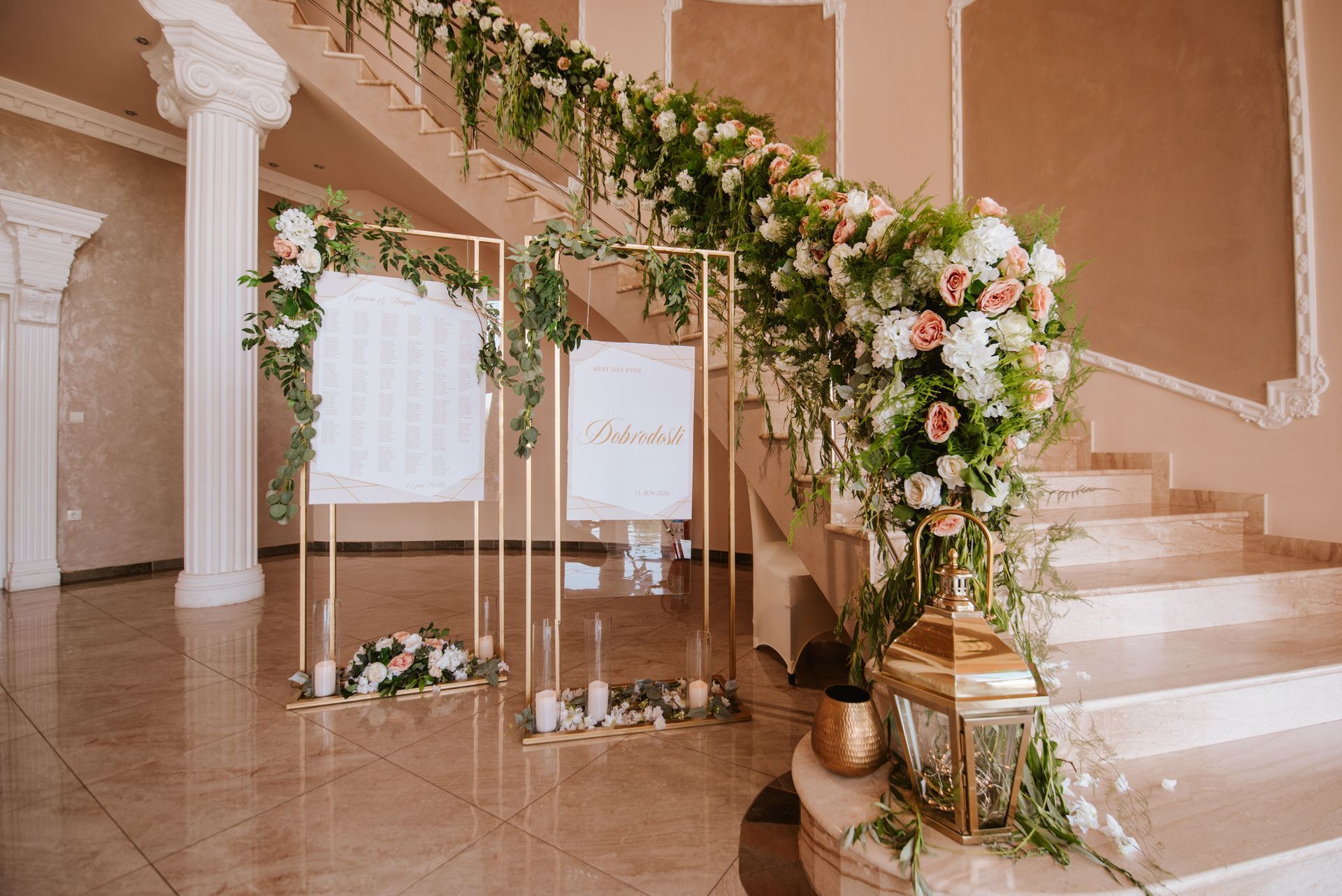 Panneau de bienvenue de mariage et compositions florales sur un grand escalier, teintes dorées et décor élégant.