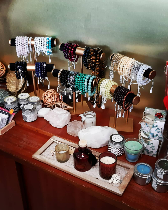 Présentoir à bijoux avec bracelets de perles, bougies et cristaux sur une étagère en bois.