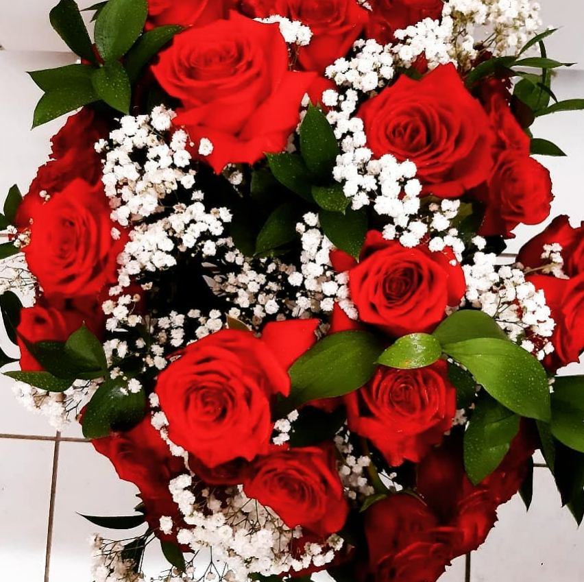 Roses rouges avec gypsophile blanc et feuilles vertes, une composition florale vibrante.