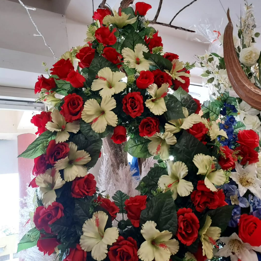 Couronne de roses rouges et de fleurs d'hibiscus crème avec des feuilles vertes ; à l'intérieur.