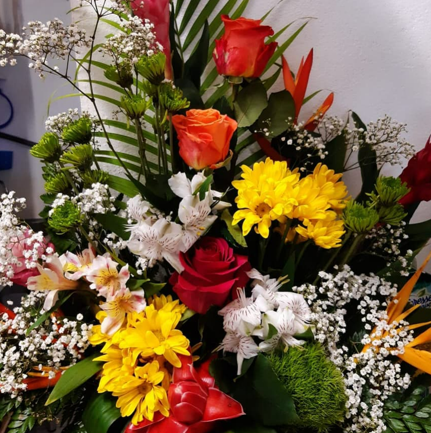 Composition florale colorée avec des roses, des lys et de la verdure.