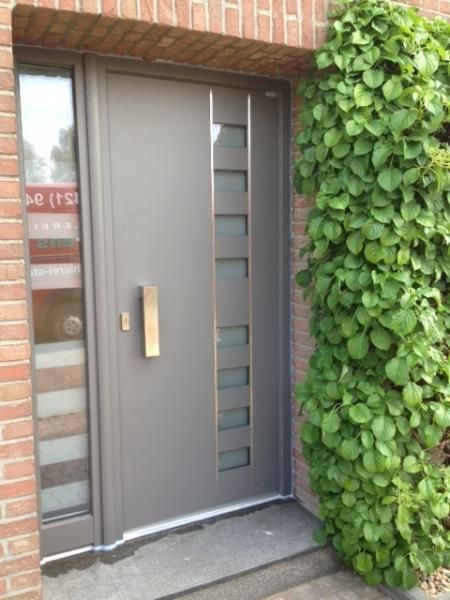 Ein Backsteingebäude mit einer grauen Tür und einem Busch davor