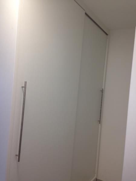 Eine weiße Wand mit einer Glasschiebetür in einem Flur.