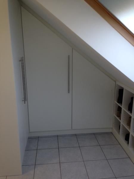 Ein Raum mit Dachschräge und weißen Schränken