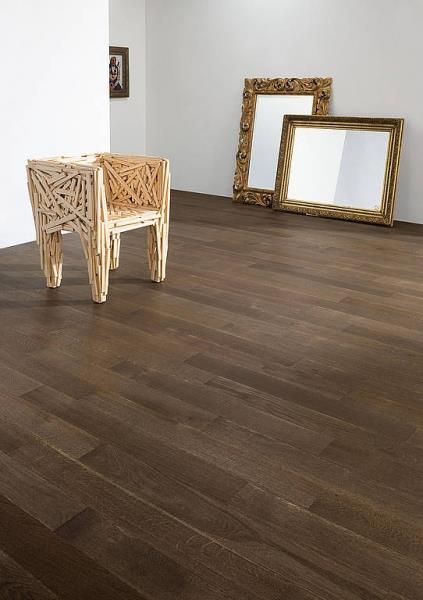 Ein Holzstuhl steht auf einem Holzboden neben zwei Spiegeln.