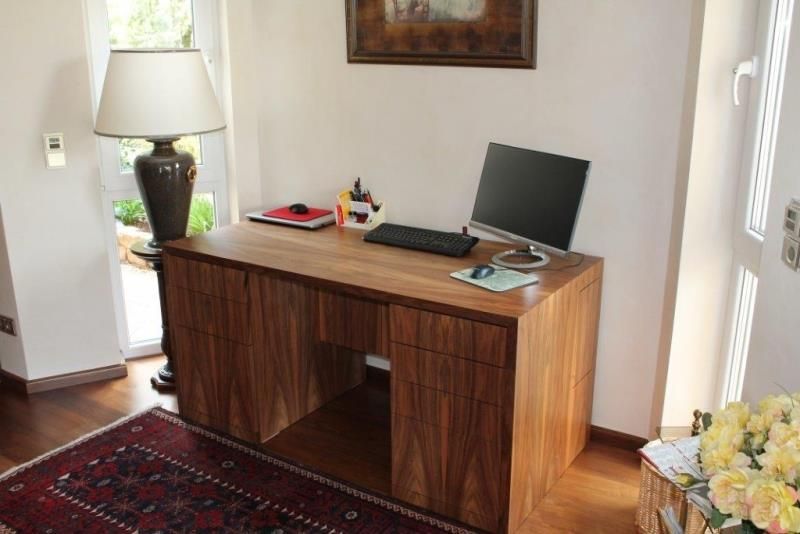 Ein Holzschreibtisch mit einem Computer und einer Lampe darauf