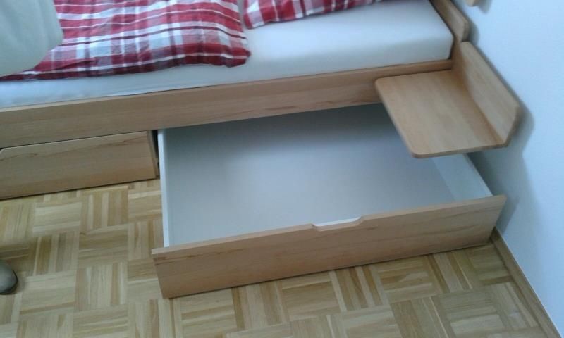 Ein Holzbett mit einer Schublade darunter