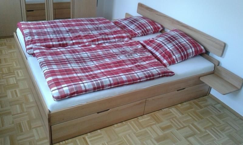 Ein Bett mit rot-weiß karierten Laken und Kissen