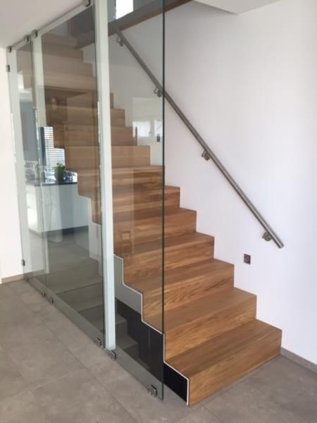 Eine Holztreppe mit einem Glasgeländer in einem Raum