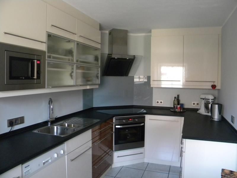 Eine Küche mit weißen Schränken und schwarzen Arbeitsplatten