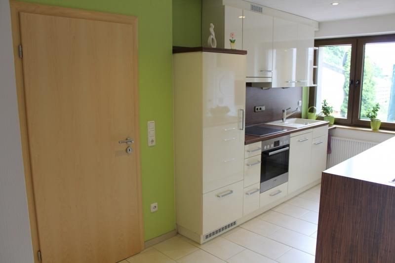 Eine Küche mit weißen Schränken und einer grünen Wand