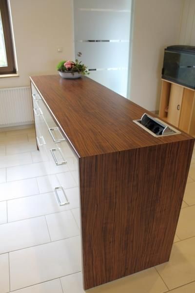 Ein langer Holztisch mit Schubladen und einer Vase mit Blumen darauf.