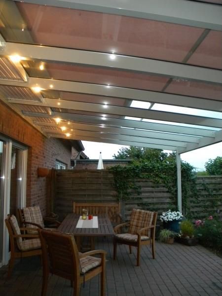 Eine Terrasse mit Tisch und Stühlen unter einem Baldachin