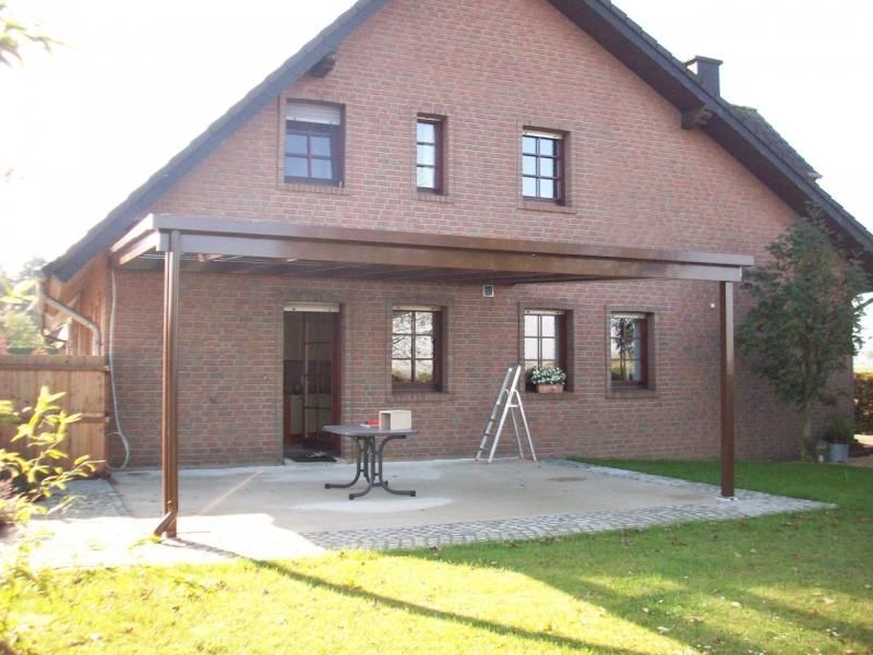 Ein Backsteinhaus mit einer Pergola und einem Tisch davor