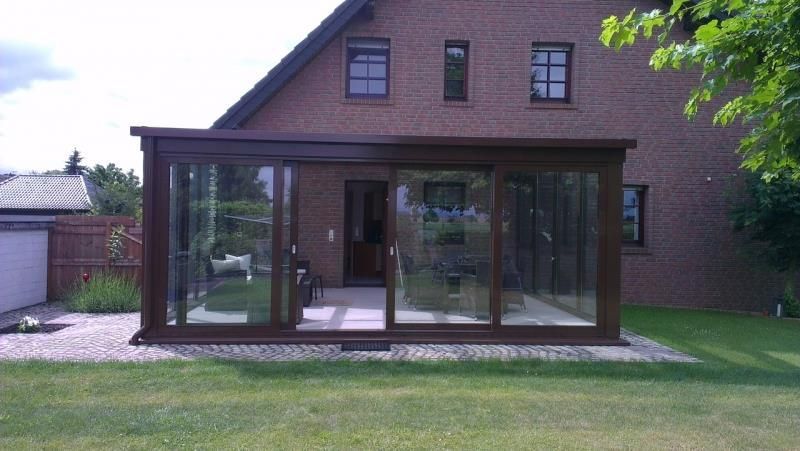 Ein Backsteinhaus mit einem großen Glasraum davor