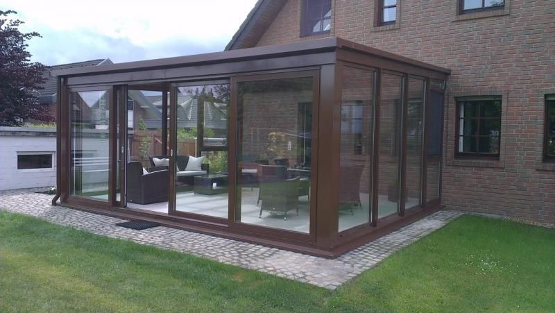 Ein Backsteinhaus mit einem großen Glasraum im Hinterhof