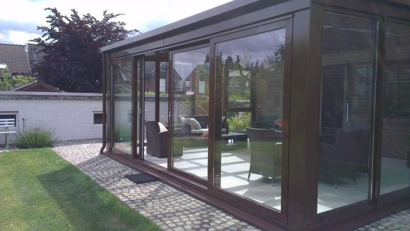 Ein Raum mit vielen Fenstern und einer Terrasse im Hinterhof