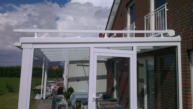 Ein Backsteinhaus mit einer weißen Pergola darauf