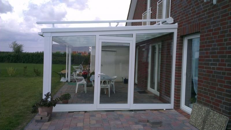 Ein Backsteinhaus mit einer weißen Veranda mit Tisch und Stühlen.