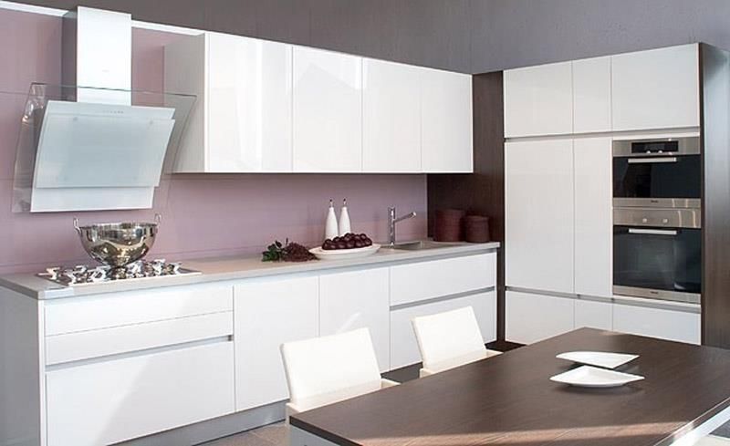 Eine Küche mit weißen Schränken und einem Holztisch