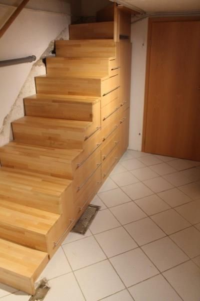 Eine Holztreppe mit Schubladen darunter in einem Raum.