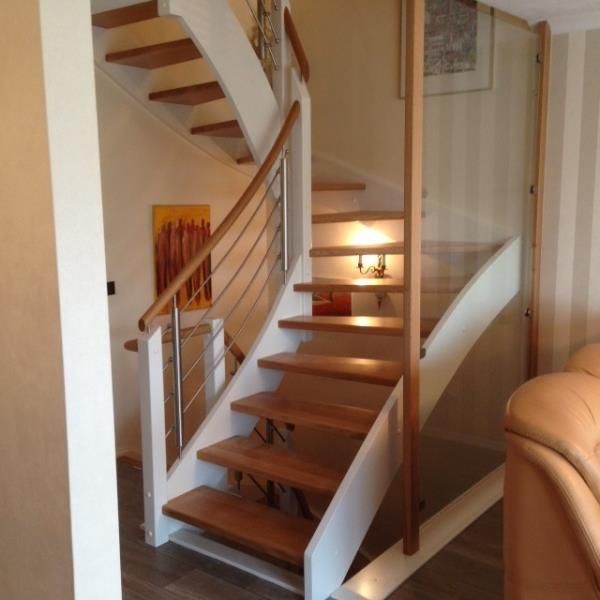 Eine Holztreppe mit Glasgeländer in einem Wohnzimmer