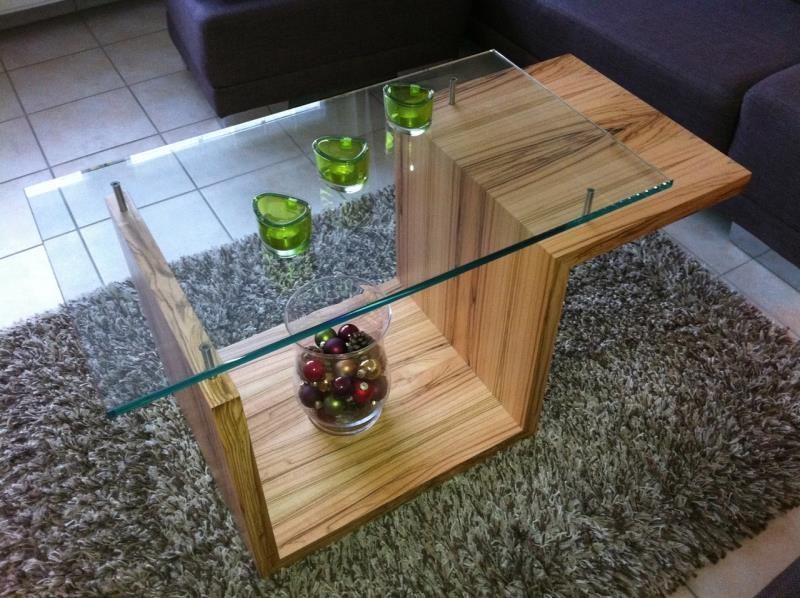 Ein Couchtisch aus Holz mit Glasplatte steht auf einem Teppich
