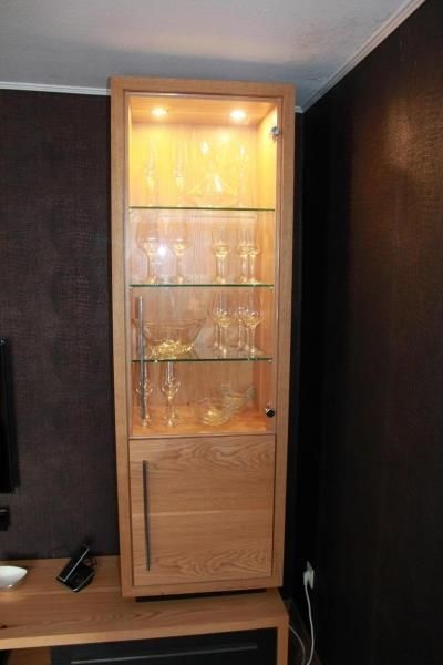 Ein Holzschrank mit Glastür und Regalen voller Weingläser.