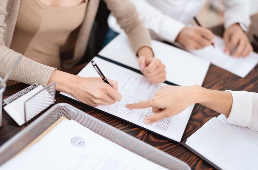 Un grupo de personas está sentada en una mesa firmando papeles.