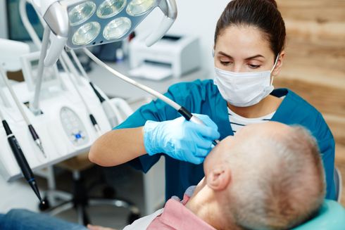 Una dentista examina los dientes de un hombre en un consultorio dental.
