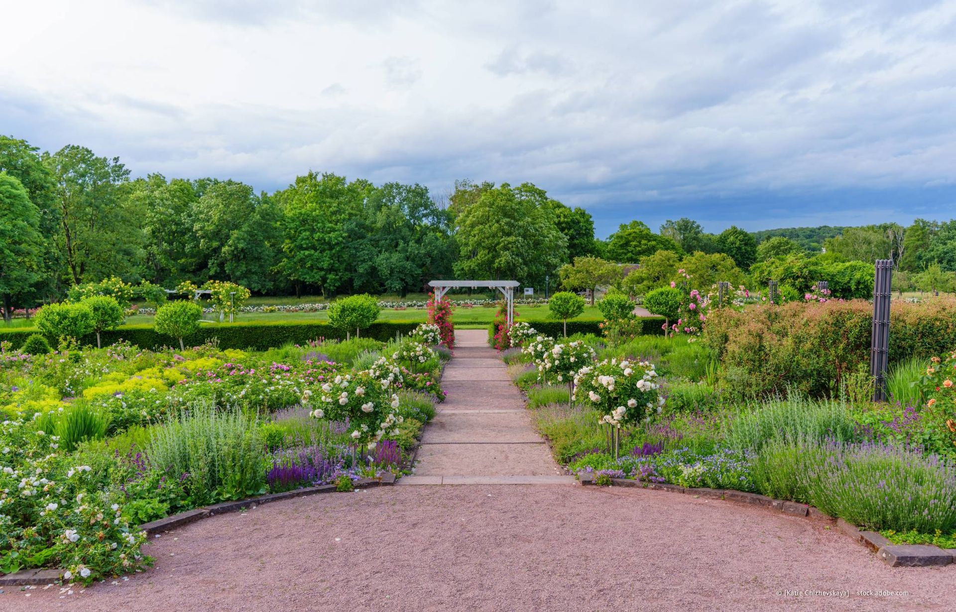 Großes Haus mit blauer Fassade, grünem Rasen, gepflegten Sträuchern und einem gepflasterten Gehweg.